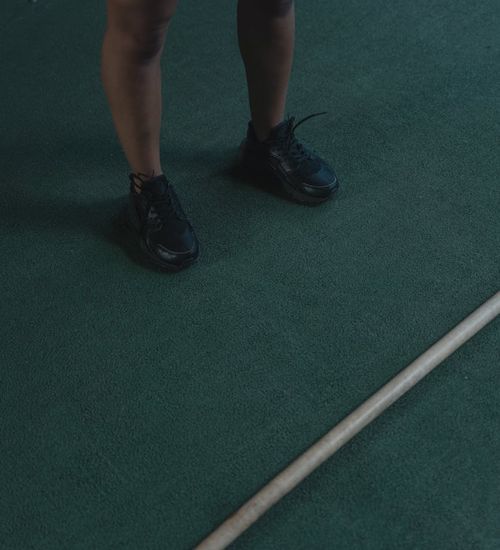 Close-up shot of feet in athletic shoes on a wooden floor, suggesting readiness for exercise.